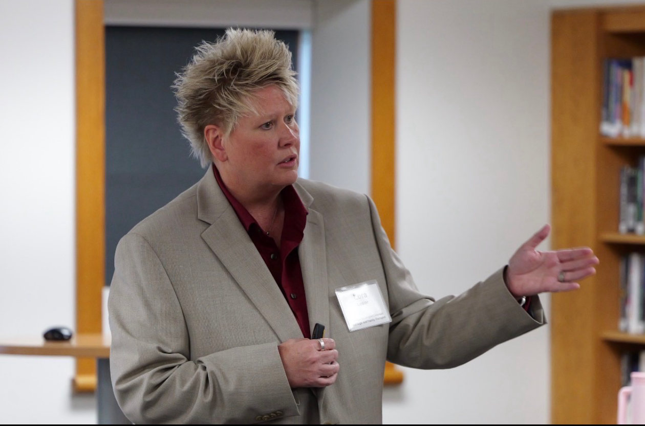 Lora E. Losier facilitating professional training, speaking with an extended hand gesture